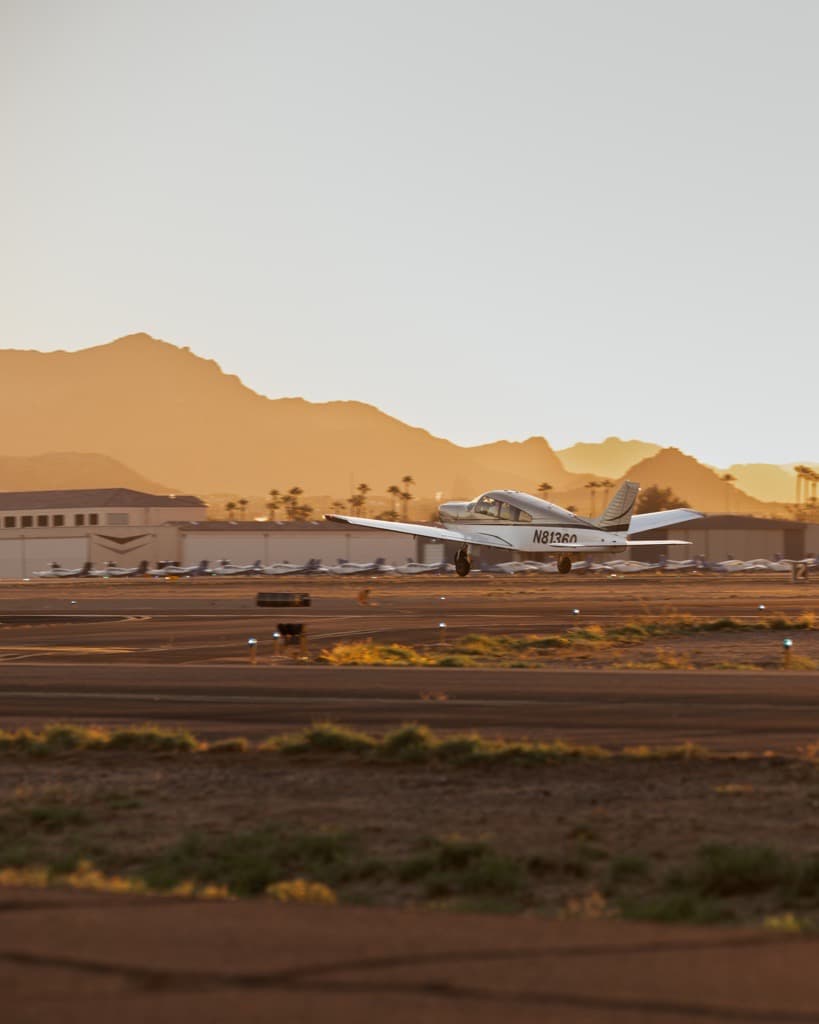 Piper lifting off the runway at sunset